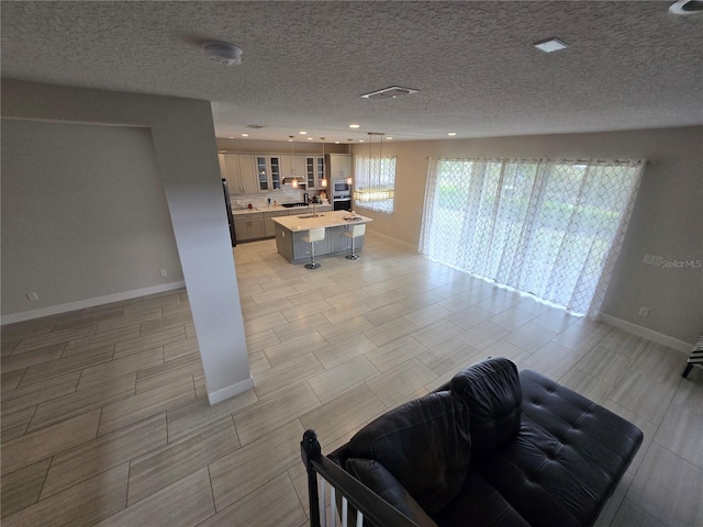 living room featuring recessed lighting, baseboards, and a textured ceiling