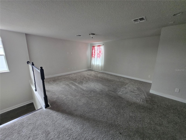 carpeted empty room with visible vents, baseboards, and a textured ceiling