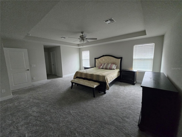 bedroom with visible vents, a raised ceiling, multiple windows, and carpet floors