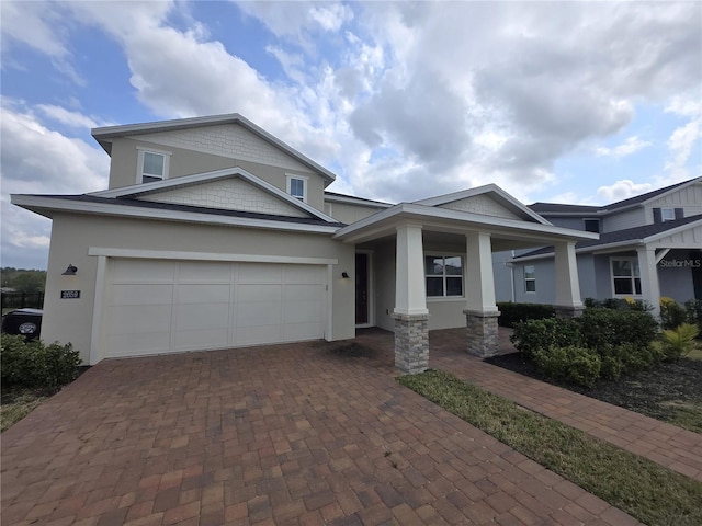 view of front of home with covered porch, stucco siding, decorative driveway, and a garage