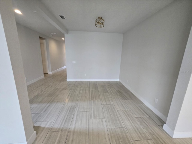 empty room with visible vents, baseboards, and wood tiled floor