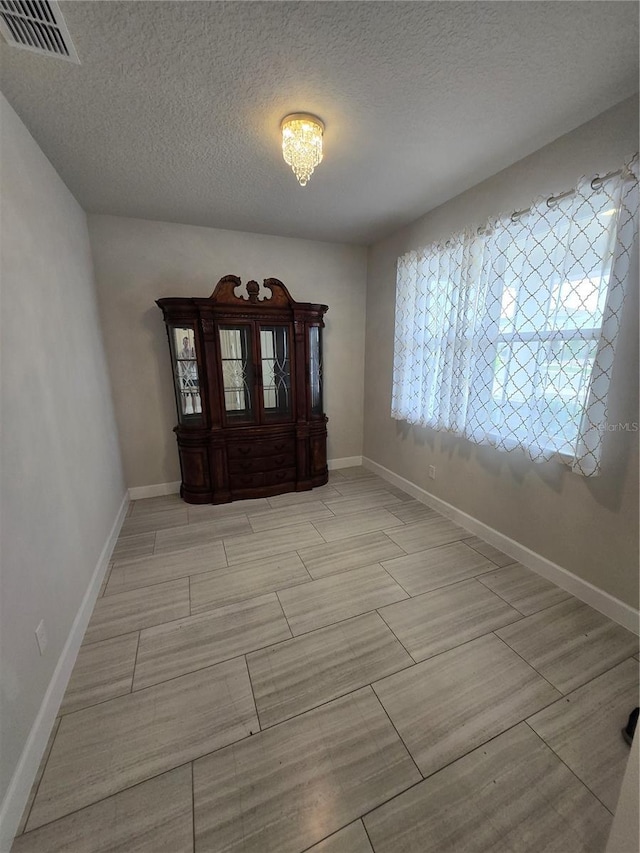 foyer featuring baseboards, visible vents, a textured ceiling, and wood finish floors