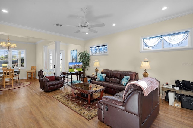 living room with crown molding, light hardwood / wood-style floors, ceiling fan with notable chandelier, and decorative columns