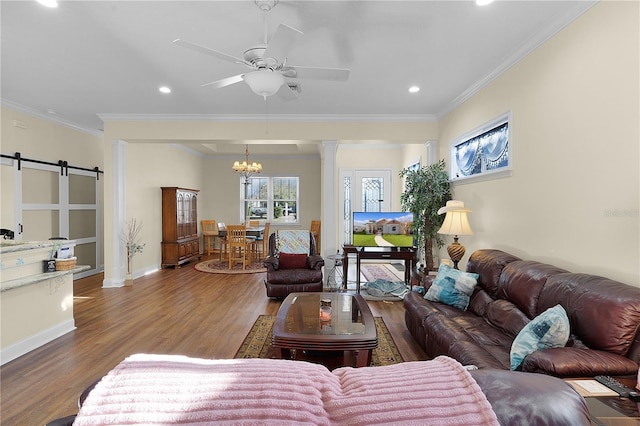 living room with dark hardwood / wood-style flooring, crown molding, a barn door, and ceiling fan with notable chandelier