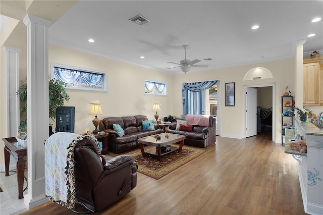 living room with ceiling fan, ornate columns, ornamental molding, and light hardwood / wood-style floors