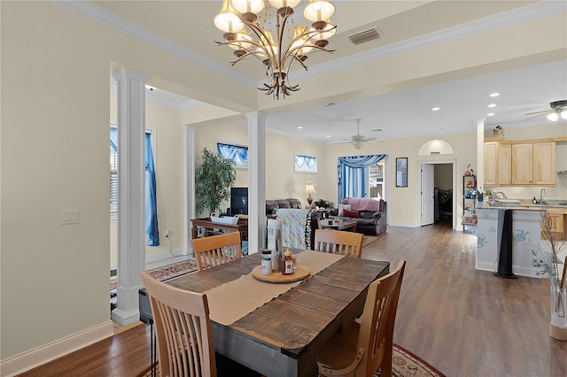 dining room with ornate columns, crown molding, dark hardwood / wood-style floors, and ceiling fan with notable chandelier