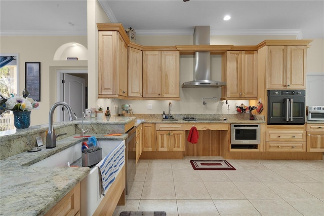 kitchen featuring light brown cabinetry, light tile floors, appliances with stainless steel finishes, light stone countertops, and wall chimney range hood