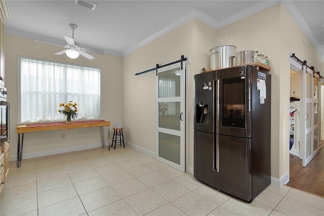 kitchen with a barn door, black refrigerator with ice dispenser, light tile floors, and ceiling fan