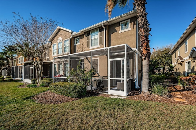 rear view of property with a yard and a sunroom