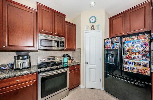 kitchen featuring light tile patterned flooring, appliances with stainless steel finishes, decorative backsplash, and dark stone countertops