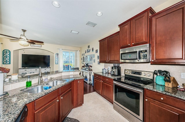 kitchen with sink, stone counters, and appliances with stainless steel finishes