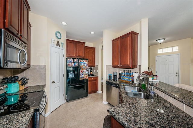 kitchen with stainless steel appliances, tasteful backsplash, sink, and dark stone counters