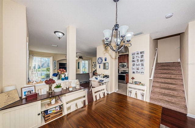 dining area featuring wood-type flooring and ceiling fan with notable chandelier