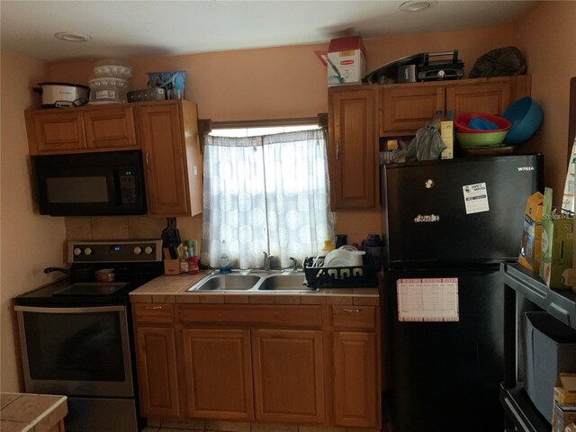 kitchen with tile countertops, black appliances, and sink