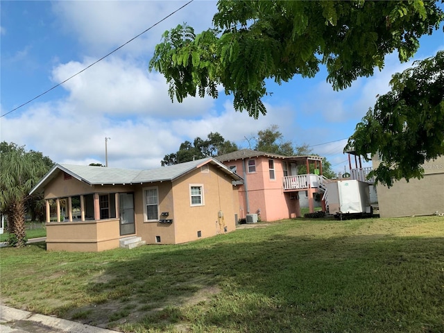 rear view of house with central AC unit and a yard