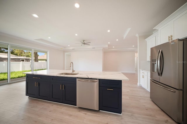 kitchen with an island with sink, ceiling fan, white cabinets, appliances with stainless steel finishes, and light wood-type flooring