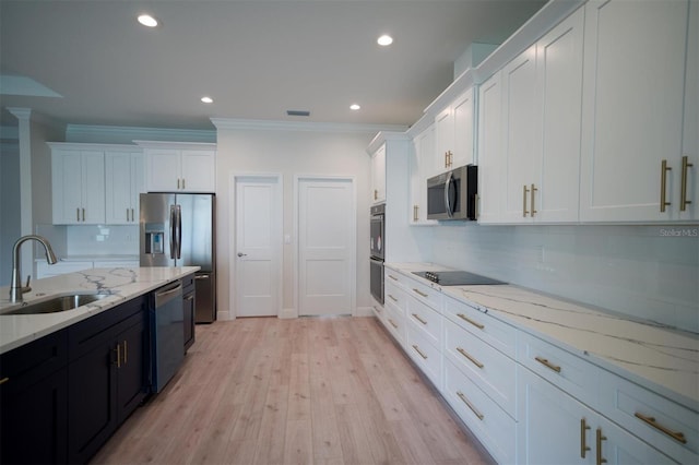 kitchen featuring sink, stainless steel appliances, tasteful backsplash, white cabinetry, and light wood-type flooring