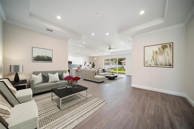 living room with ceiling fan, crown molding, a raised ceiling, and hardwood / wood-style flooring