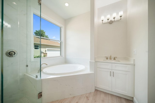 bathroom featuring tiled bath, hardwood / wood-style floors, and vanity