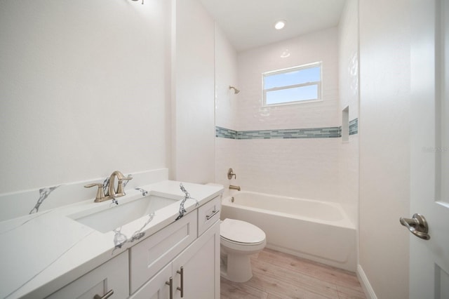 full bathroom with hardwood / wood-style flooring, vanity, toilet, and tiled shower / bath