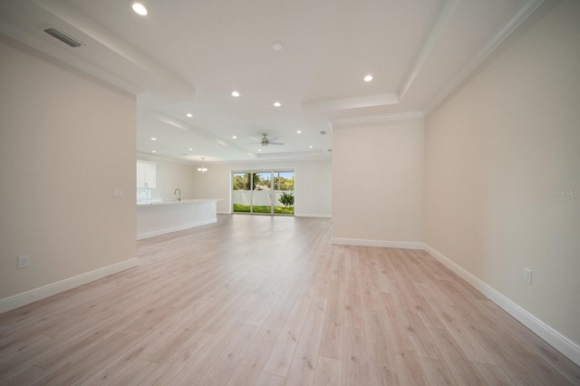 unfurnished room with a raised ceiling, light hardwood / wood-style floors, ceiling fan, and sink