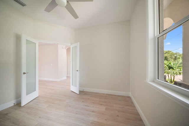 empty room with ceiling fan, light hardwood / wood-style flooring, and french doors