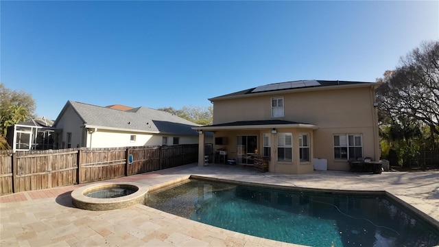 rear view of house featuring a swimming pool with hot tub, solar panels, a patio area, and central air condition unit