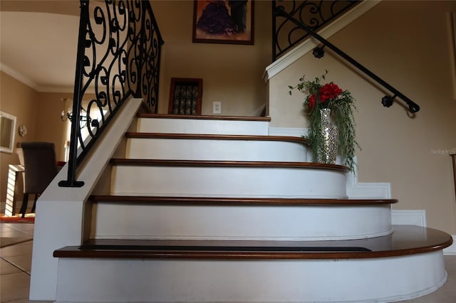 stairs with tile floors and crown molding