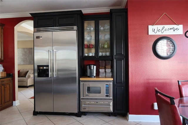 kitchen with crown molding, built in appliances, and light tile floors