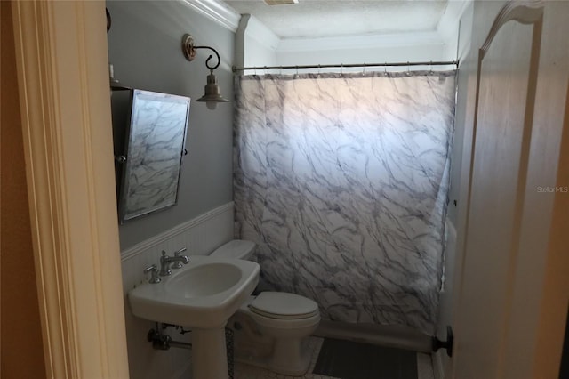 bathroom featuring a textured ceiling, crown molding, and toilet