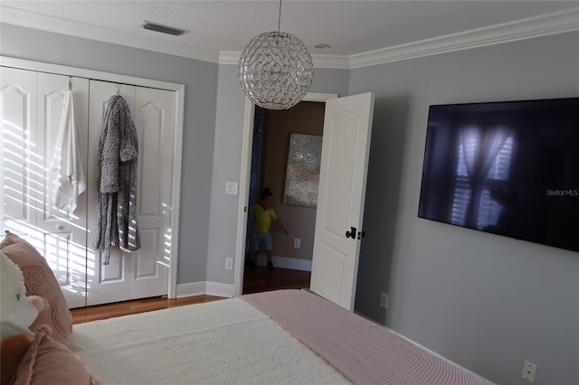 bedroom featuring crown molding, a closet, dark hardwood / wood-style floors, and a chandelier