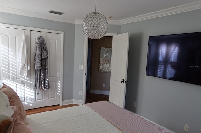 bedroom featuring dark hardwood / wood-style flooring, crown molding, a closet, and an inviting chandelier