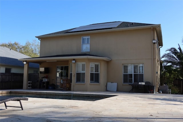 back of property featuring a fenced in pool, solar panels, and a patio area