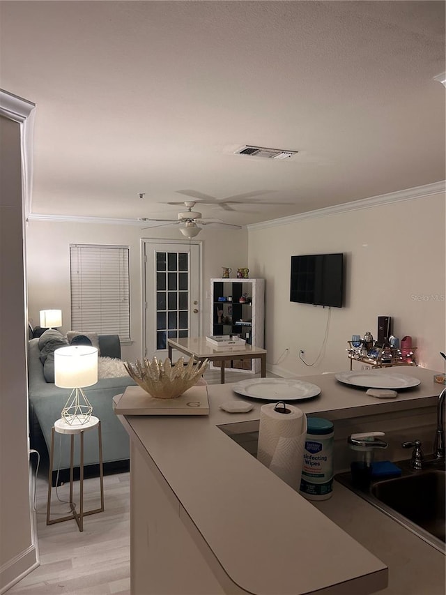 kitchen with ceiling fan, crown molding, sink, and light wood-type flooring