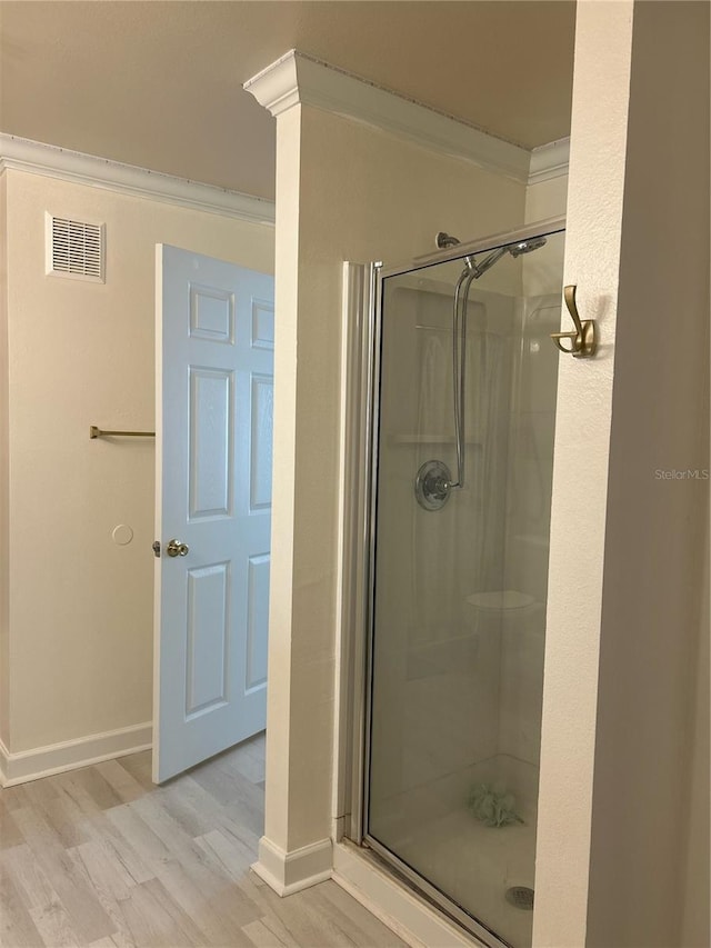 bathroom featuring wood-type flooring, a shower with door, and crown molding