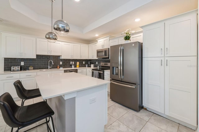 kitchen with backsplash, a tray ceiling, appliances with stainless steel finishes, sink, and white cabinets