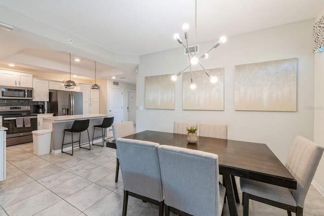 dining area with a tray ceiling, a notable chandelier, and light tile floors