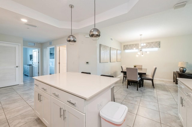 kitchen featuring white cabinetry, a tray ceiling, an inviting chandelier, a kitchen island, and pendant lighting