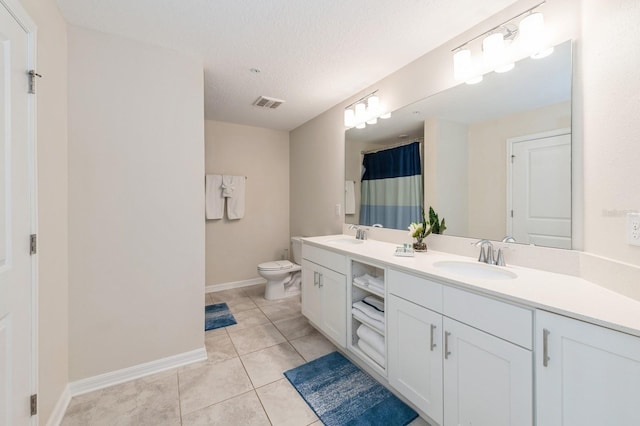 bathroom featuring tile flooring, a textured ceiling, double vanity, and toilet