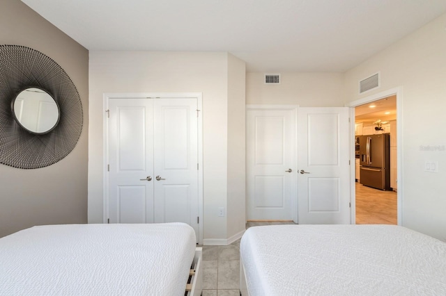 bedroom featuring stainless steel fridge and light tile floors