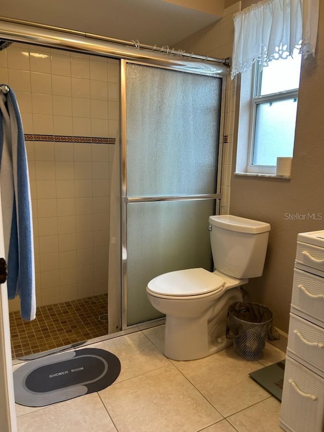 bathroom with tile patterned flooring, toilet, and an enclosed shower