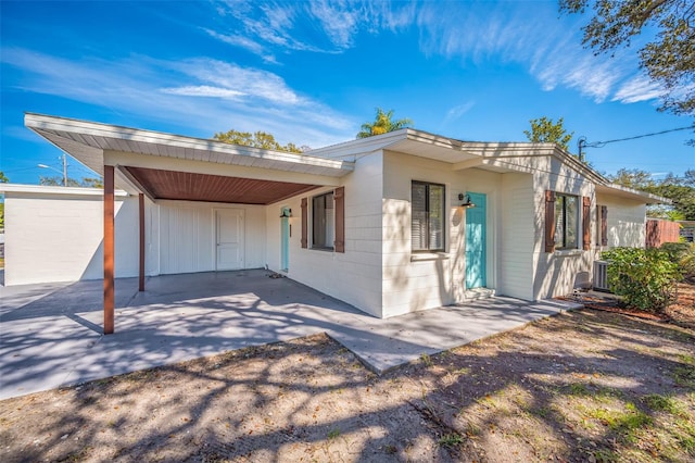 rear view of property featuring a carport and central AC