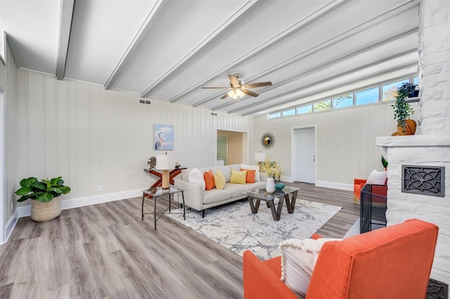 living room featuring vaulted ceiling with beams, ceiling fan, a large fireplace, and light hardwood / wood-style flooring