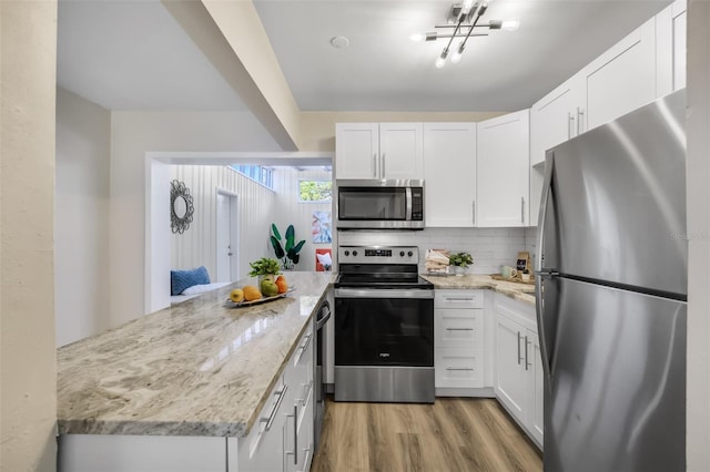 kitchen featuring white cabinetry, appliances with stainless steel finishes, light stone countertops, and light hardwood / wood-style flooring