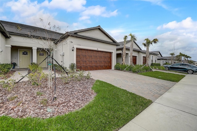 view of front of property featuring a garage, decorative driveway, and stucco siding