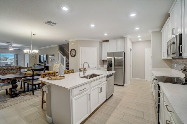 kitchen featuring ceiling fan with notable chandelier, an island with sink, hanging light fixtures, stainless steel appliances, and sink