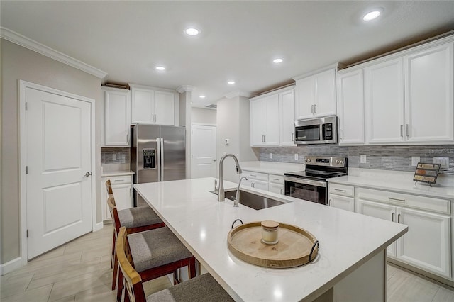 kitchen with appliances with stainless steel finishes, a breakfast bar, a sink, and light countertops