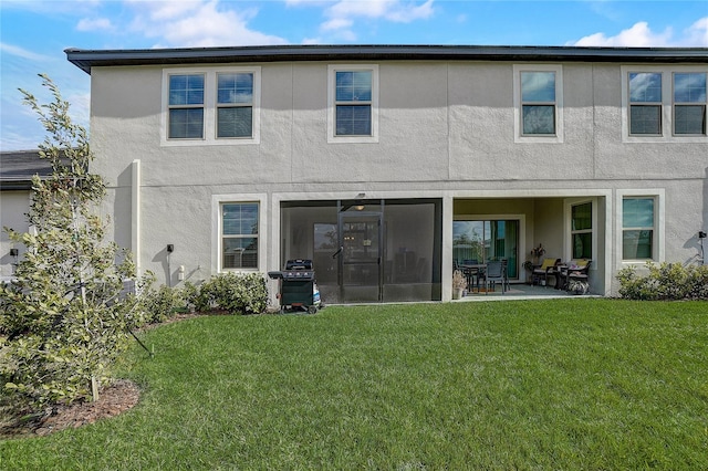 rear view of property featuring a sunroom, a lawn, a patio, and stucco siding