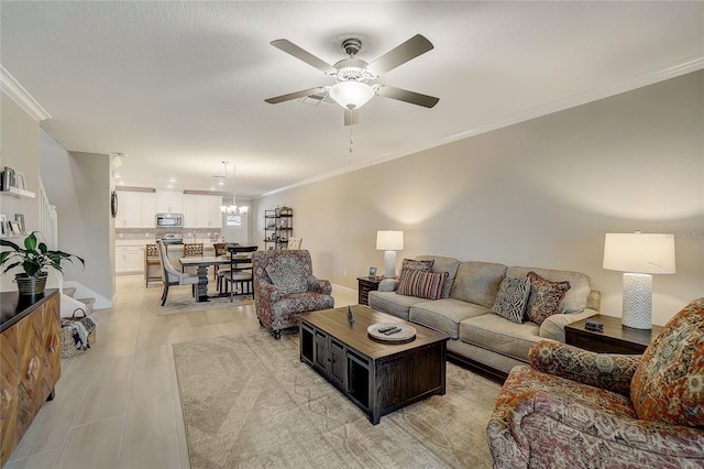 living room featuring ceiling fan with notable chandelier, ornamental molding, and baseboards