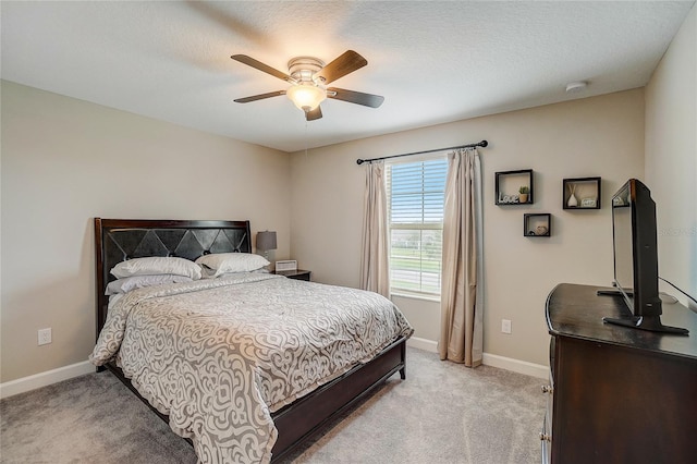 bedroom with light carpet, ceiling fan, a textured ceiling, and baseboards